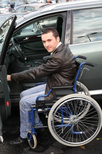 Jovem em cadeira de rodas entrando em seu carro — Fotografia de Stock