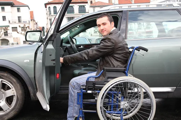 Молодой человек в инвалидной коляске садится в машину — стоковое фото