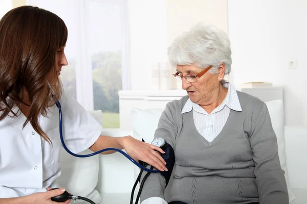Primer plano de la enfermera que revisa la presión arterial de la mujer mayor — Foto de Stock