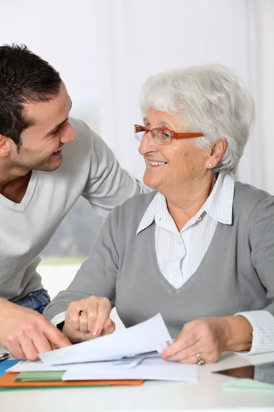 Young man helping elderly woman with paperwork — Stock Photo, Image