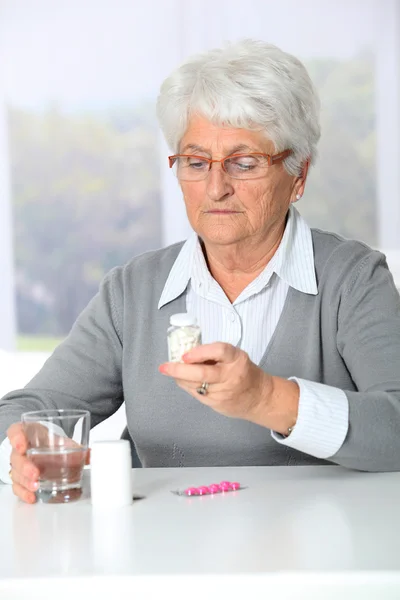 Närbild av gamla kvinnan tittar på medicin flaskor — Stockfoto