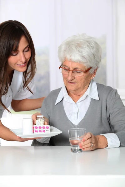 Nurse bringing medicine to elderly woman — Stock Photo, Image