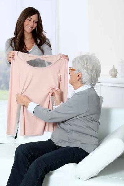 Jonge vrouw tonen nieuwe kleren aan grootmoeder — Stockfoto