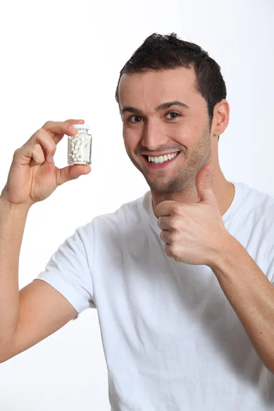 Fechar-se de homem sorridente segurando garrafa de pílulas — Fotografia de Stock
