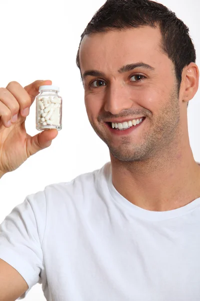 Fechar-se de homem sorridente segurando garrafa de pílulas — Fotografia de Stock