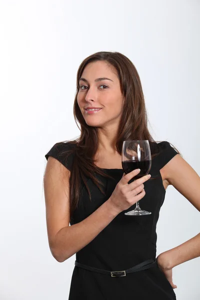 Beautiful woman in black dress tasting red wine — Stock Photo, Image