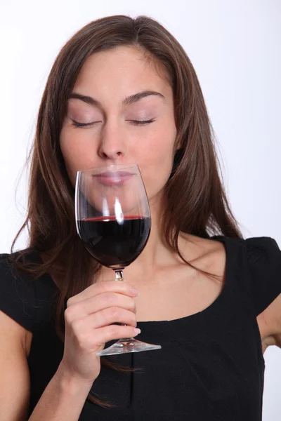 Piękna kobieta w czarnej sukni, degustacja wina czerwonego — Zdjęcie stockowe
