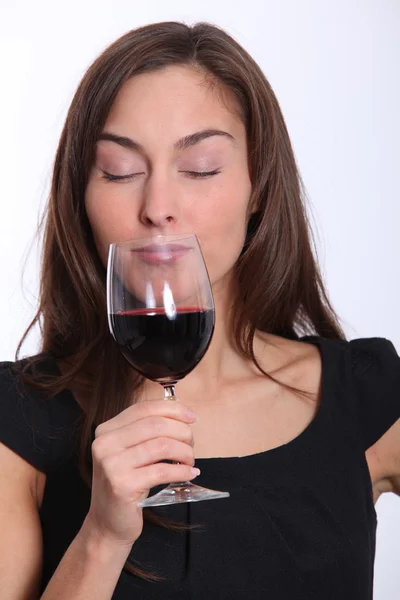 Beautiful woman in black dress tasting red wine — Stock Photo, Image