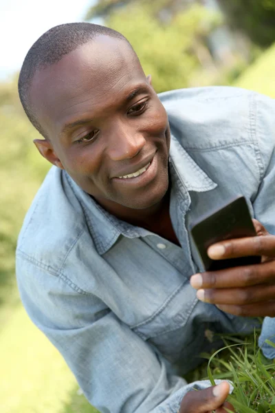 Muž, kterým se stanoví v parku s mobilním telefonem Royalty Free Stock Fotografie