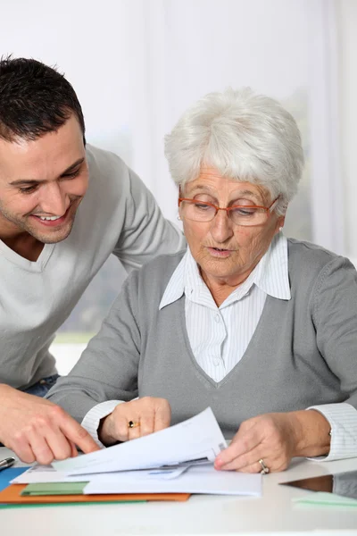 Young man helping elderly woman with paperwork Stock Picture