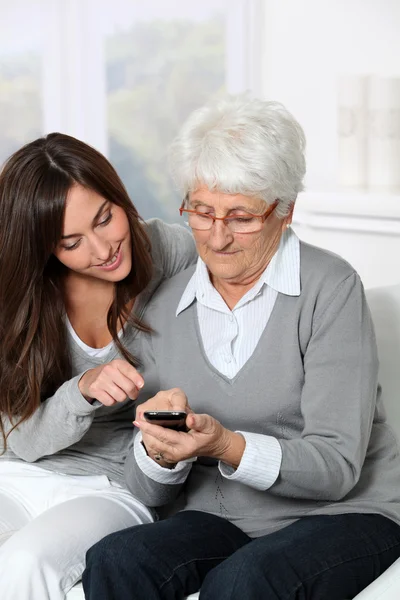 Young woman showing how to use mobile phone to grandmother — Stock Photo, Image
