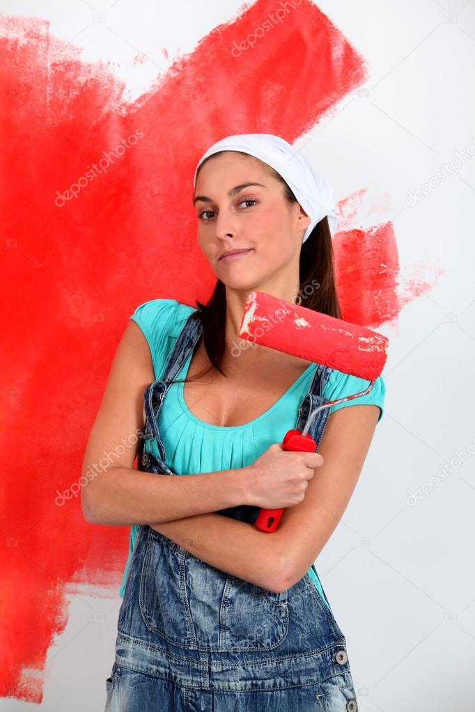 Young woman painting house wall in red
