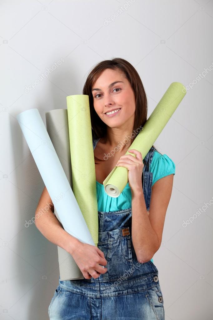 Beautiful young woman holding wallpaper rolls