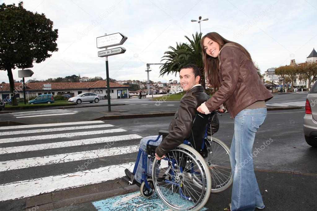 Woman helping friend in wheelchair cross the street