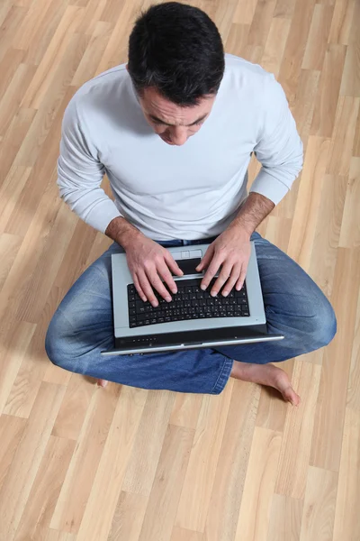 Man sitter på golvet med bärbar dator — Stockfoto