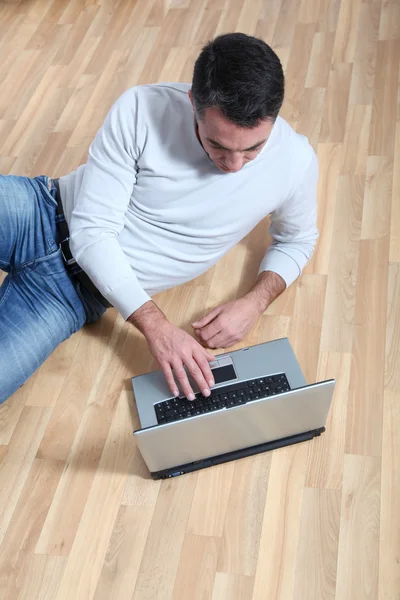 Hombre sentado en el suelo con ordenador portátil — Foto de Stock