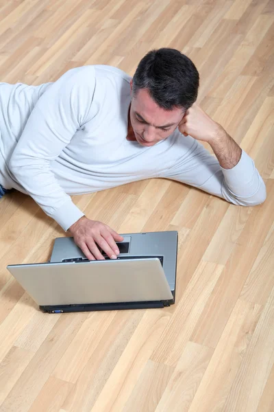 男子坐在地板上有便携式计算机上 — 图库照片