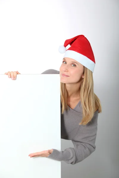 Mujer rubia con sombrero de Santa mostrando pizarra blanca — Foto de Stock