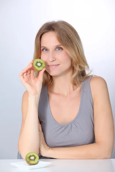 Beautiful blond woman eating kiwis — Stock Photo, Image