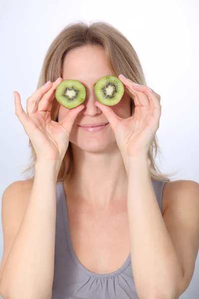 Beautiful blond woman eating kiwis — Stockfoto