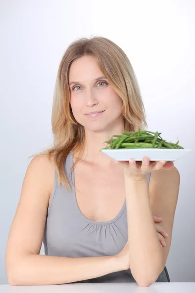 Frau vor Teller mit grünen Bohnen — Stockfoto