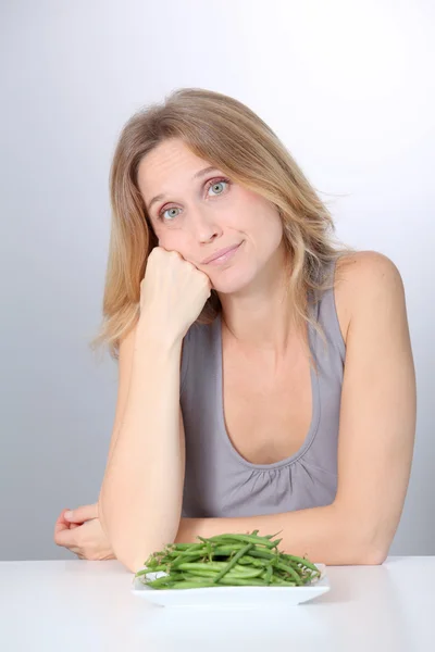Mulher infeliz na frente de feijão verde — Fotografia de Stock