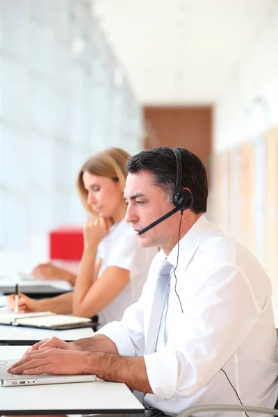 Business working in front of computer with headphones — Stock Photo, Image