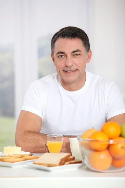 Smiling adult man having breakfast — Stock Photo, Image