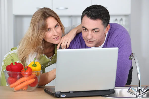 Paar in Küche sucht Kochrezepte — Stockfoto