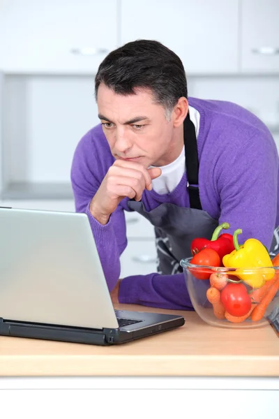 Hombre en la cocina con ordenador portátil — Foto de Stock