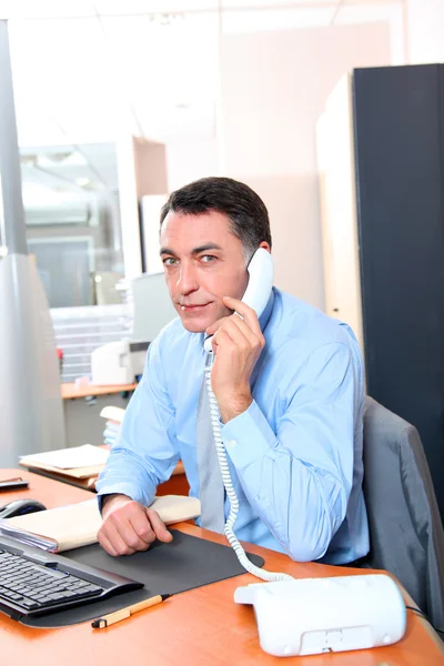 Бизнесмен в офисе разговаривает по телефону — стоковое фото
