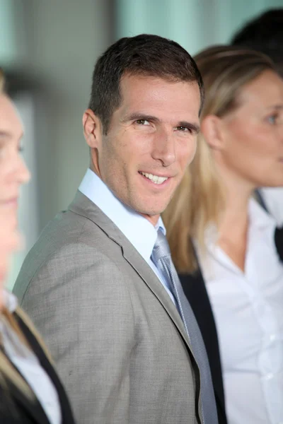 Smiling businessman in front of group — Stock Photo, Image