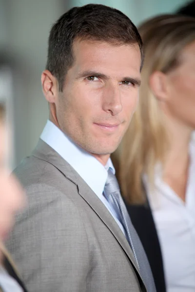 Smiling businessman in front of group — Stock Photo, Image