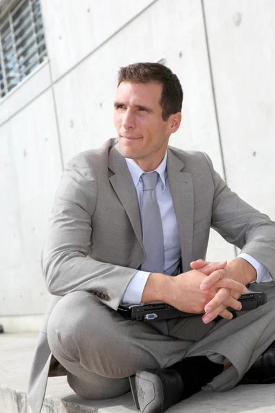 Salesman sitting cross-legged in front of building — Stock Photo, Image