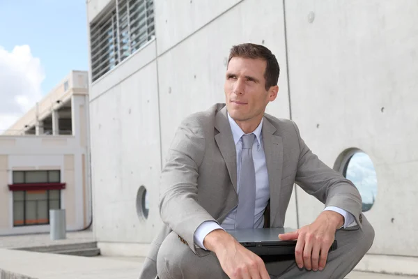 Salesman sitting cross-legged in front of building — Stock Photo, Image
