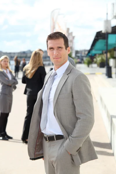 Businessman standing outdoors in the entrance of international fair — Stock Photo, Image