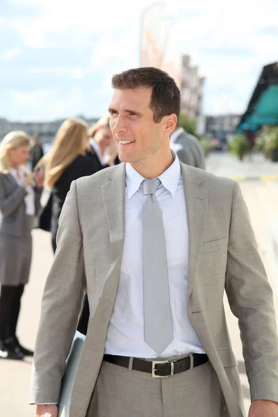 Businessman standing outdoors in the entrance of international fair — Stock Photo, Image