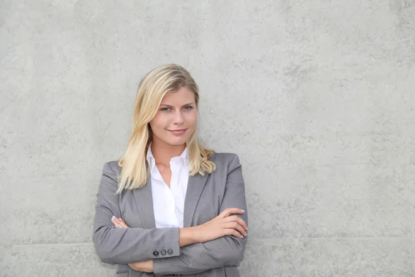 Blond businesswoman standing against a wall — Stock Photo, Image