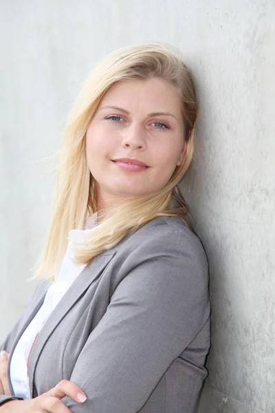 Blonde Geschäftsfrau steht gegen eine Wand — Stockfoto