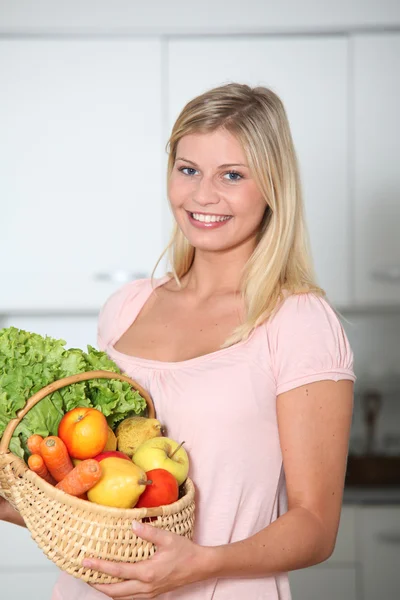 Smiling woman holding basket of organic food — Zdjęcie stockowe