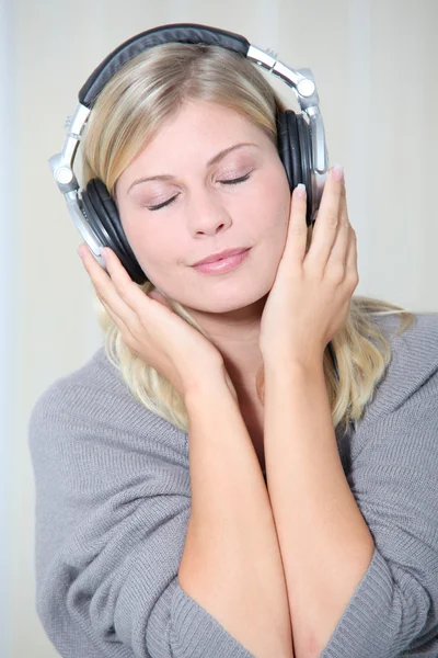 Vacker blond kvinna hemma med hörlurar på — Stockfoto