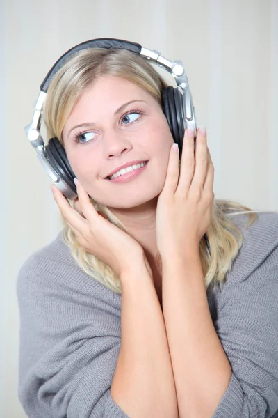 Vacker blond kvinna hemma med hörlurar på — Stockfoto