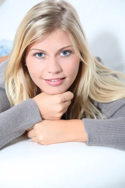 Lächelnde schöne blonde Frau auf Sofa liegend — Stockfoto