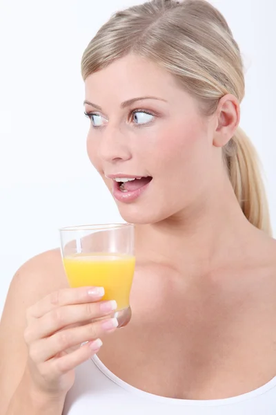 Красивая блондинка держит стакан апельсинового сока — стоковое фото
