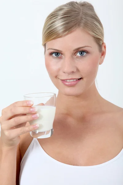 Beautiful blond woman holding glass of milk — Stock Photo, Image