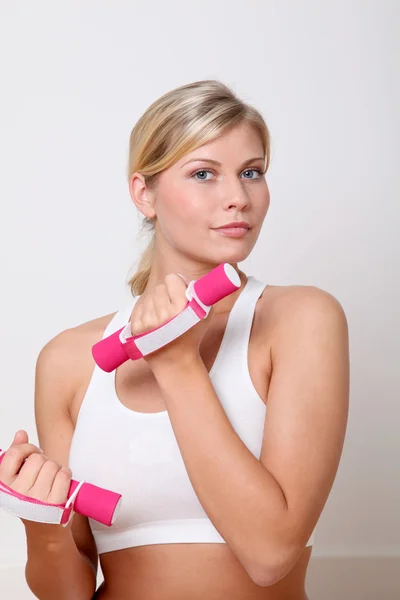 Beautiful blond woman lifting dumbbells in fitness gym — Stock Photo, Image