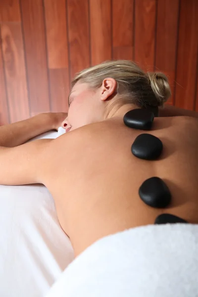 Blonde vrouw opleggen massagebed met hete stenen — Stockfoto