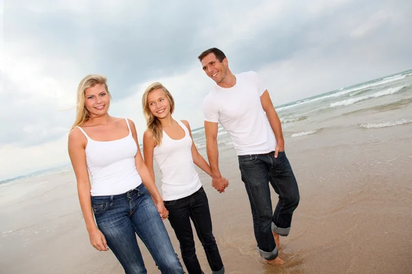 Família andando de mãos dadas em uma praia de areia — Fotografia de Stock