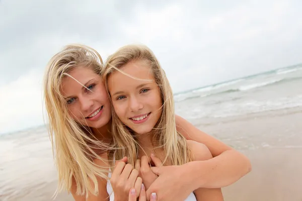 Femme blonde et jeune fille sur une plage de sable — Photo