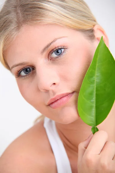 Primer plano de la hermosa mujer sosteniendo hoja de planta verde — Foto de Stock